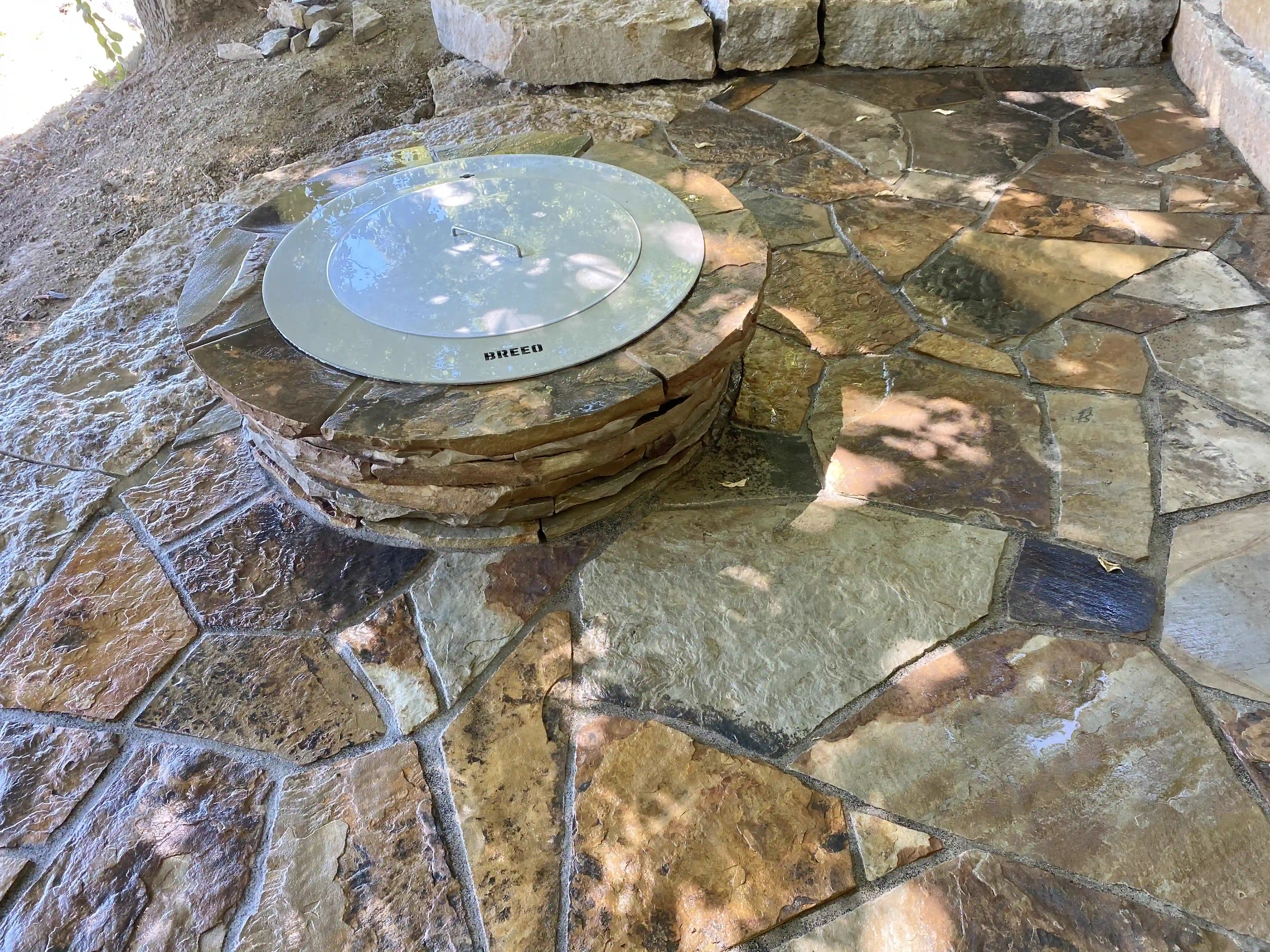 Custom stone fire pit set in a flagstone patio